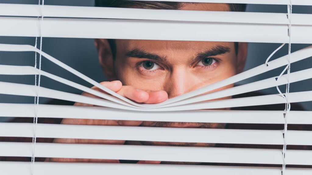 Spion spionerar genom gardiner.