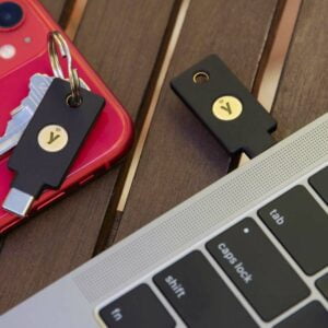 Två säkerhetsnycklar bredvid en Iphone och en Macbook Pro