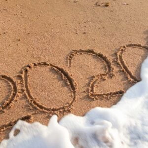 Havet spolar bort siffrorna 2020 från sandstranden.