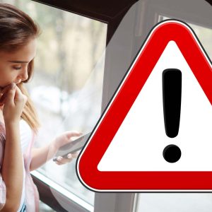 Varningsskylt framför kvinna som läser meddelande på mobil.