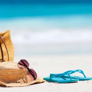 Hatt och sandaler på sandstrand