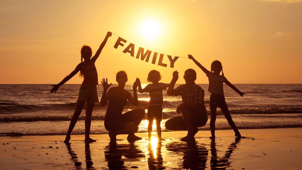 Familj på stranden vid solnedgång.