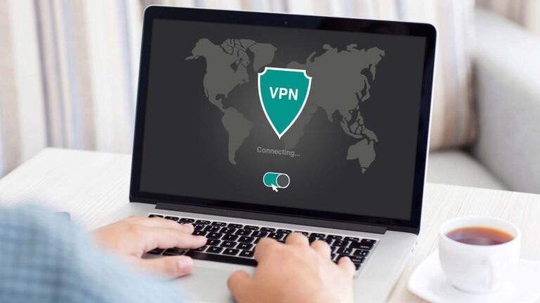 Person sitter vid sin dator med en kopp kaffe intill. På datorn visas en generisk logotyp där det står VPN.