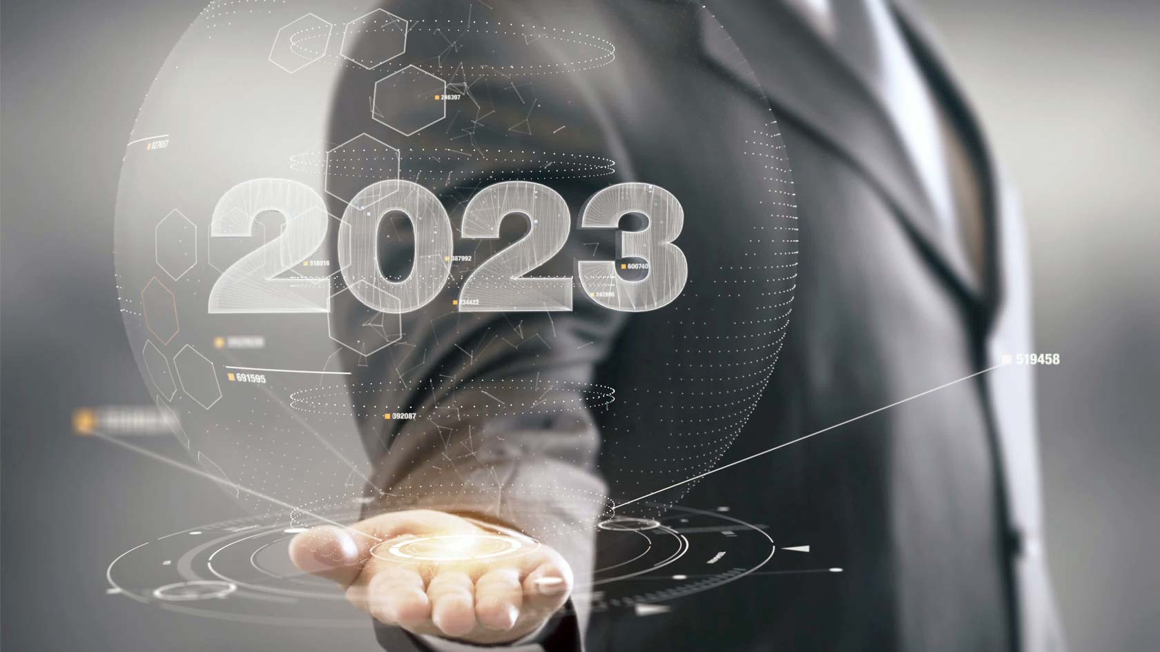En affärsklädd person håller fram en futuristisk rendering av siffran 2023.