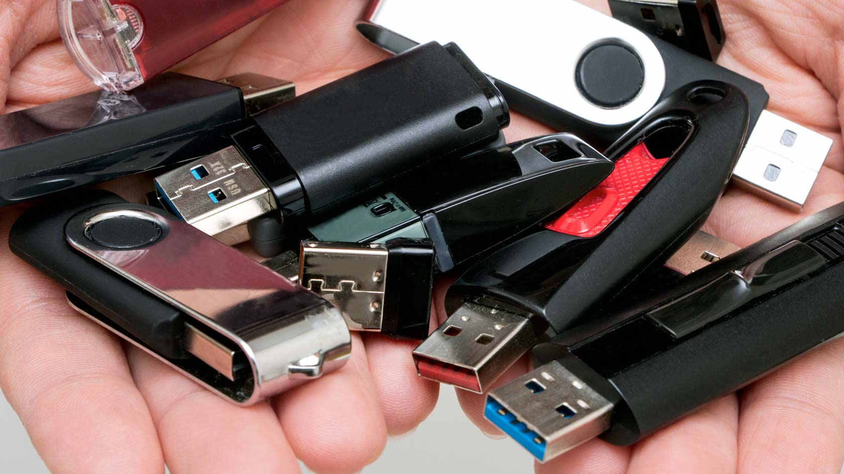 Händer fulla med olika USB-minnen.