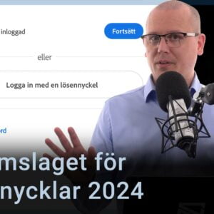 Karl Emil Nikka står vid sin mikrofon. Adobes inloggningsruta med texten ”Logga in med lösennyckel” syns i bakgrunden.