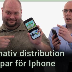 Peter och Nikka står vid sina mikrofoner. Texten ”alternativ disribution av appar för Iphone” är stämpad ovanpå. Peter håller upp en Iphone som visar en emulator som spelar Super Mario World.