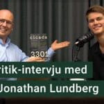 Karl Emil Nikka och Jonathan Lundberg sitter vid varsin mikrofon. Texten ”källkritik-intervju med Jonathan Lundberg” är stämplad ovanpå.
