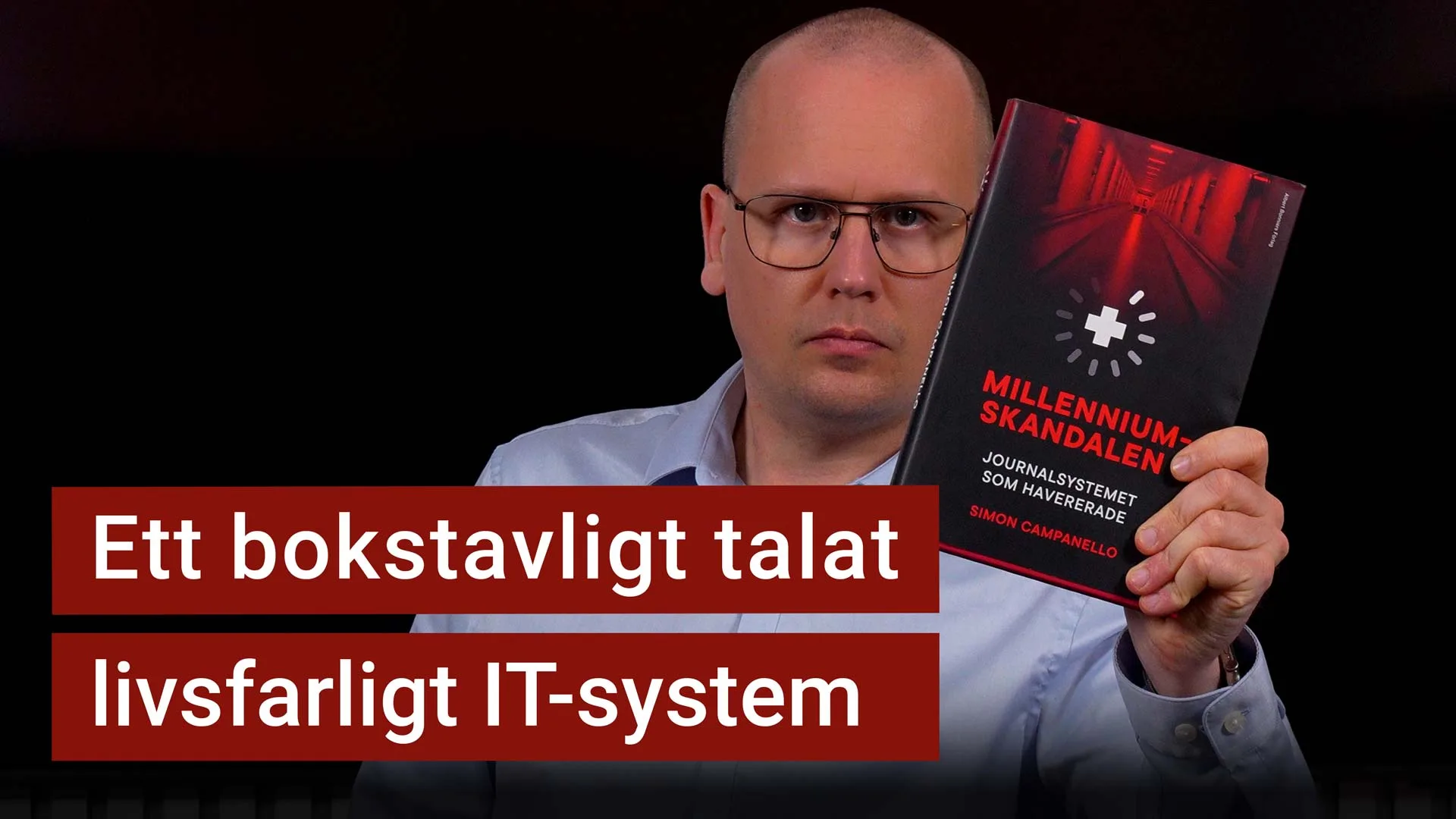 Karl Emil Nikka håller upp boken Millenniumskandalen. Texten ”ett bokstavligt talat livsfarligt IT-system” är stämplad ovanpå.